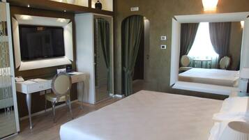 Een hotelkamer met een bed, een bureau, een stoel, een televisie en een badkamer met douchegordijn.