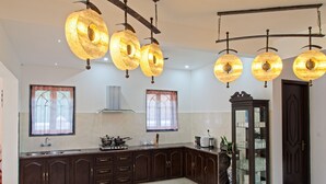 A modern kitchen with dark wooden cabinets, a built-in stove, and a large window with a view. - Villa Calangute Phase 10 (Calangute)