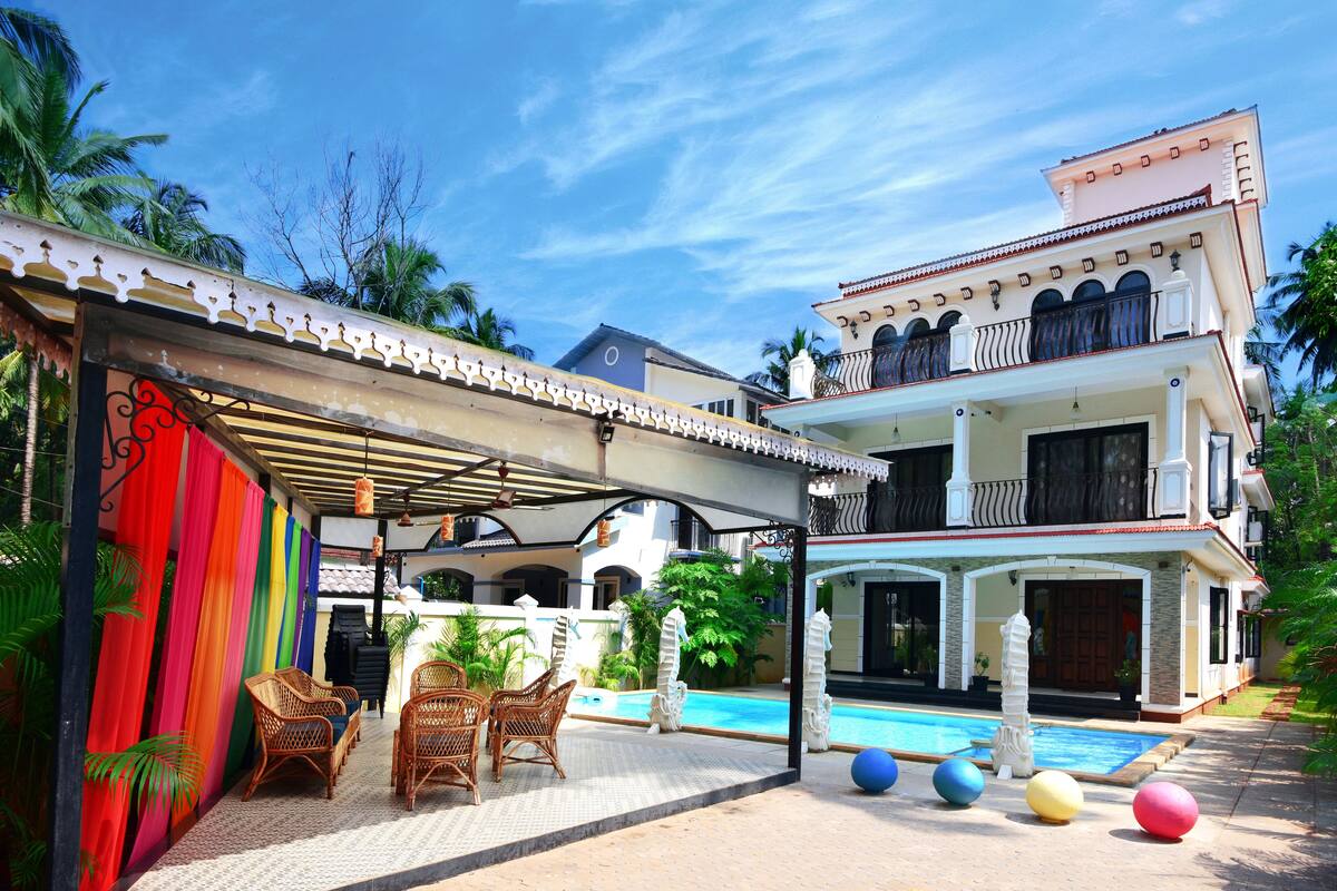 A two-story house with a swimming pool, outdoor seating, and a covered patio area.