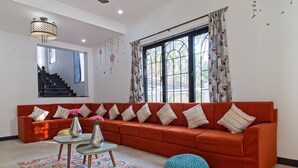 A modern living room with a red sofa, a glass coffee table, and a patterned rug. - Villa Calangute Phase 10 (Calangute)