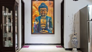 A hallway with a large Buddha painting, a glass cabinet with dishes, and a decorative vase. - Villa Calangute Phase 10 (Calangute)