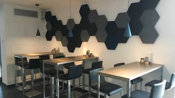 Een moderne eetruimte met zeshoekige wanddecoratie, een lange tafel en zwarte stoelen.