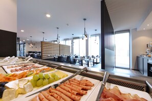 Un bufé con diversas opciones de comida, incluyendo carnes, quesos y frutas.