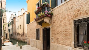 A narrow Venetian alley with a canal, stone buildings, and a wooden boat. - Ca' Lavezzera (Venice)
