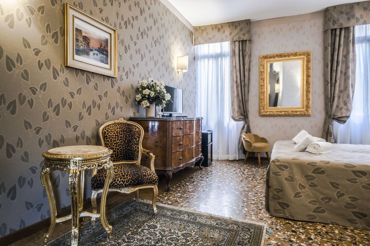 A hotel room with a bed, a chair, a dresser, a television, and a framed picture on the wall.
