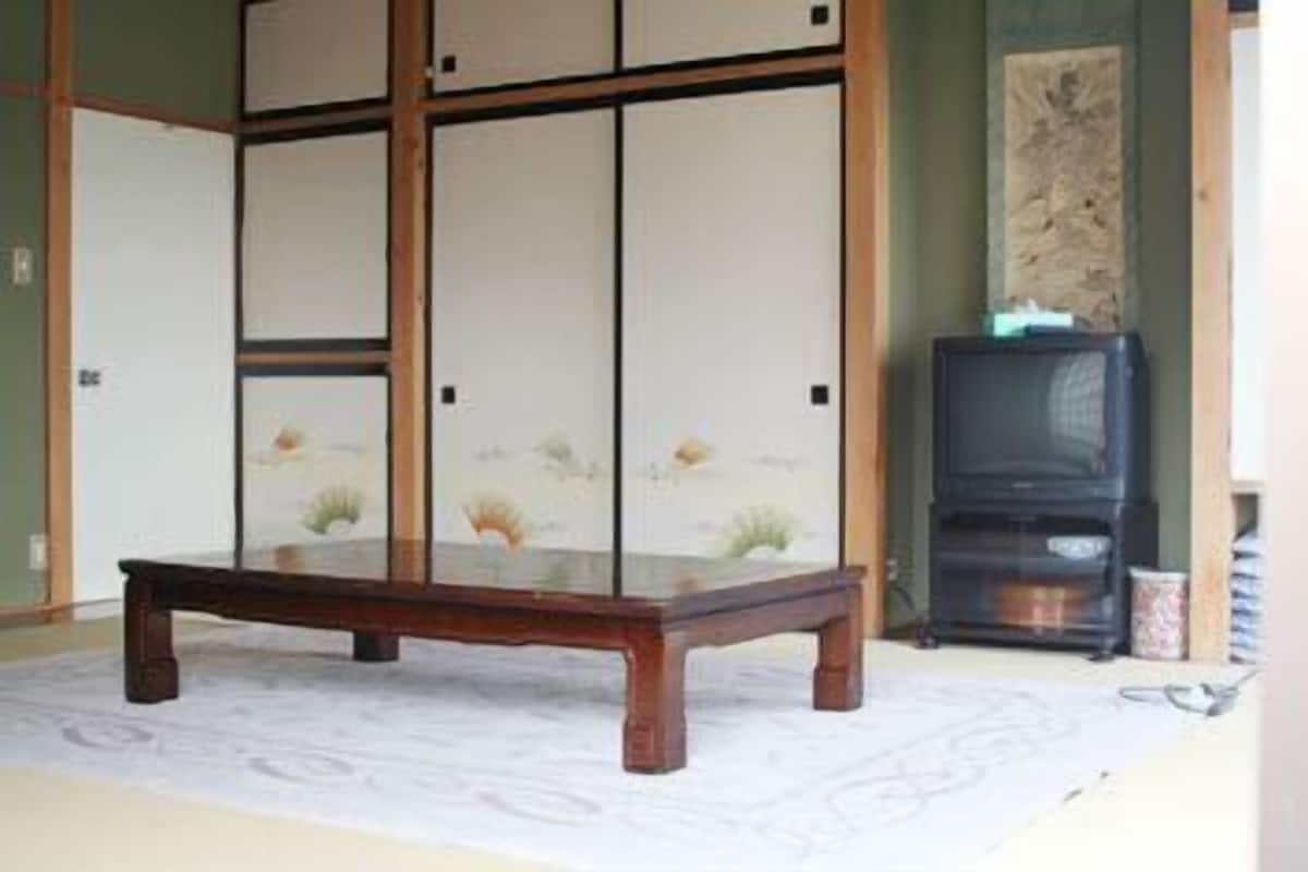 Ein traditioneller japanischer Raum mit Tatami-Boden, einem niedrigen Holztisch und einem verschiebbaren Shoji-Bildschirm mit floralen Mustern.