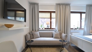 Una sala de estar moderna con un sofá, un televisor de pantalla plana, una mesita y una ventana con cortinas.