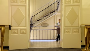 A grand staircase with a handrail and a decorative wall panel.