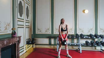 A person standing in a room with a red carpet, a fireplace, and a wall with decorative panels.