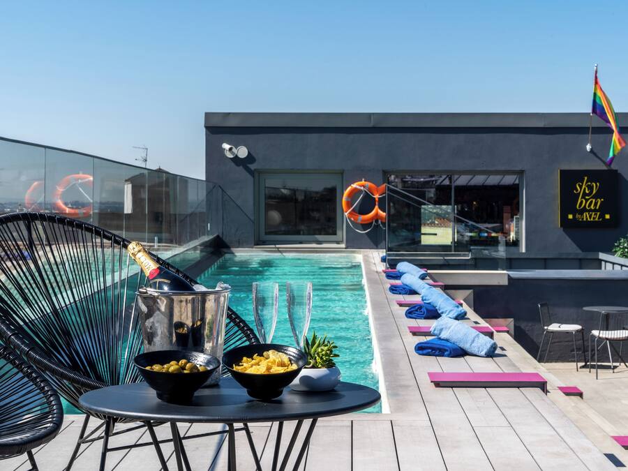 Una piscina al aire libre, sombrillas, sillones reclinables de piscina