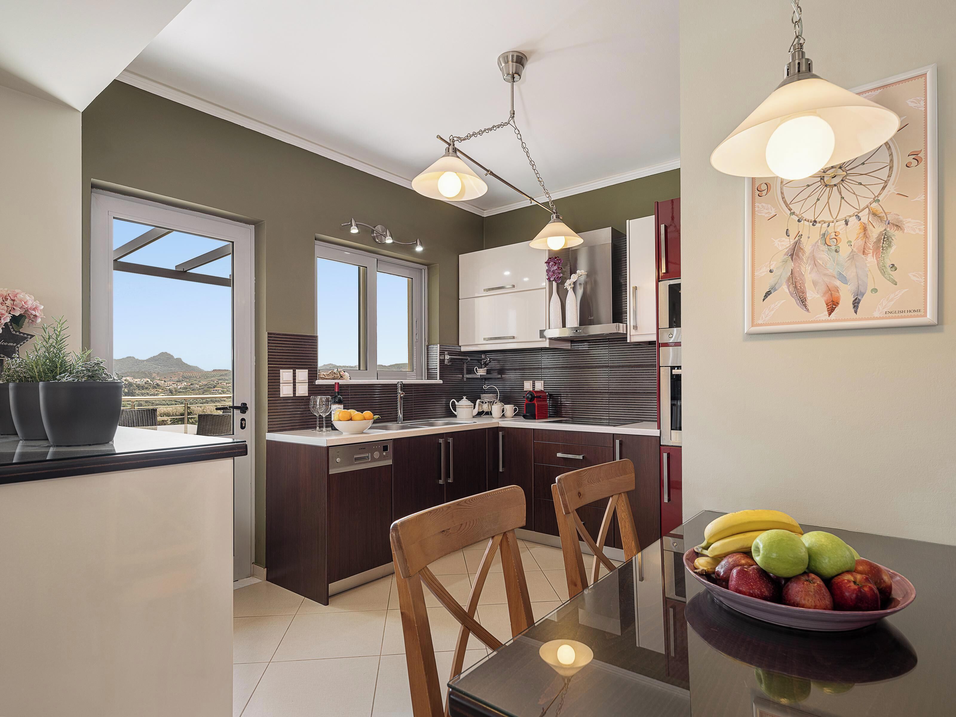A modern kitchen with dark wood cabinets, a large window, and a dining area with a glass table.