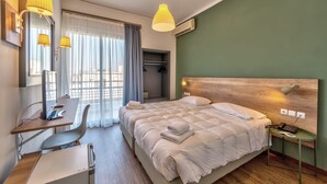 Habitación de hotel con cama, escritorio, silla y una mesita de noche con lámpara.