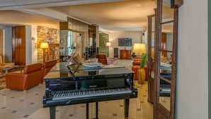 Un amplio salón con un piano de cola, asientos cómodos y una televisión.