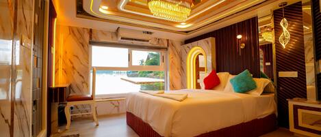 Quarto moderno com cama grande, lustre e vista para o exterior.