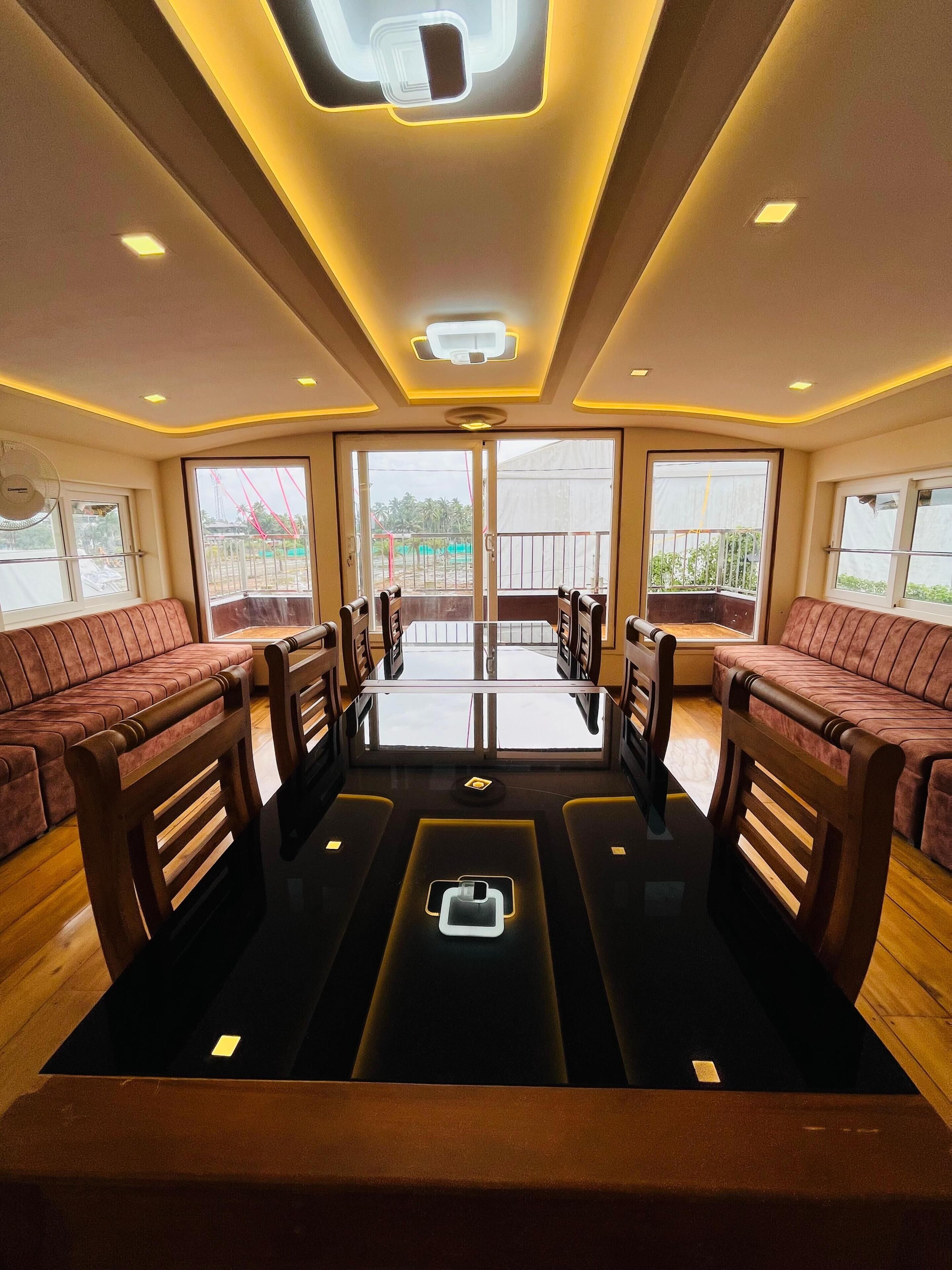 A dining area with a central table, four wooden chairs, and two sofas.