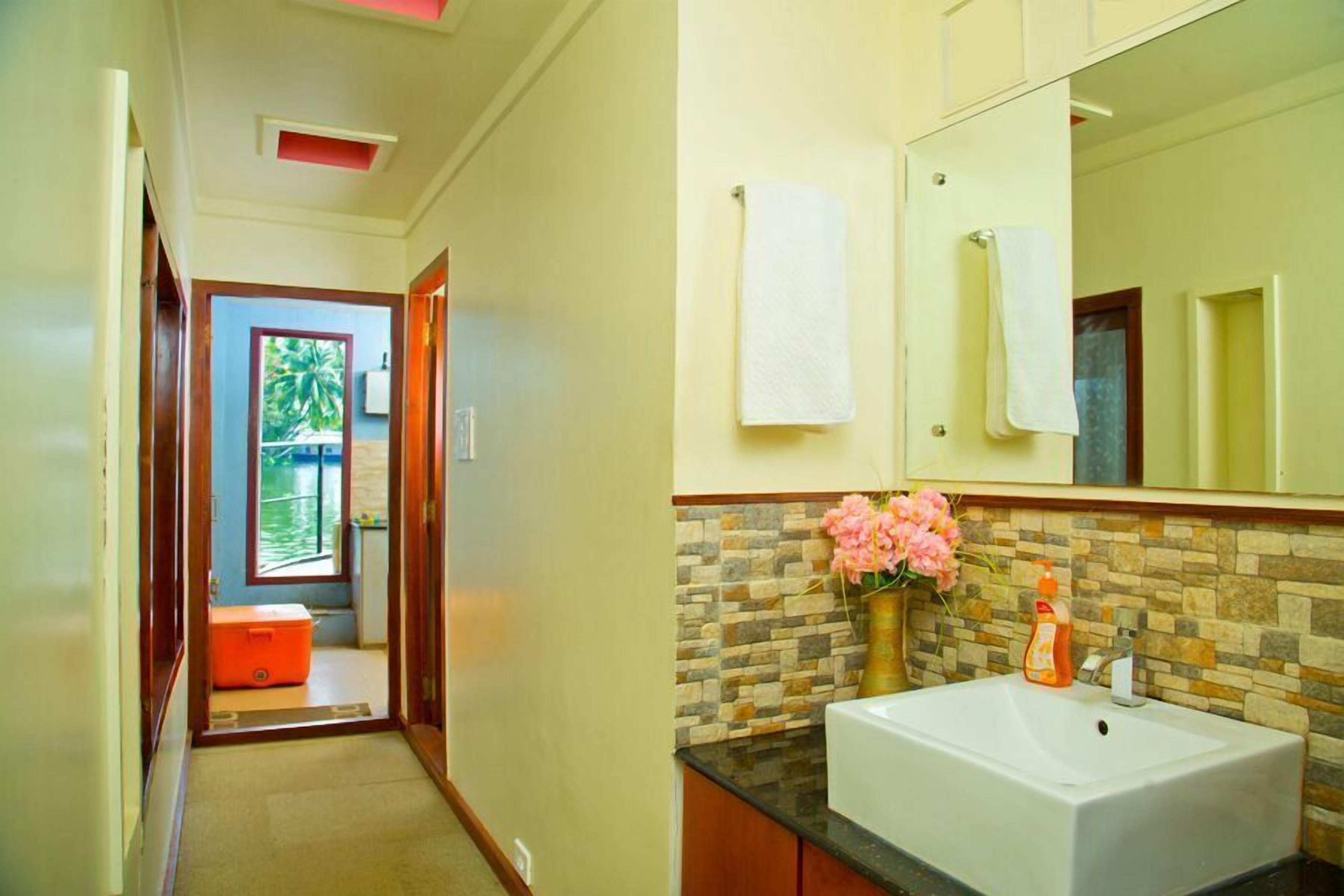 A bathroom with a white sink, a mirror, and a vase with flowers.