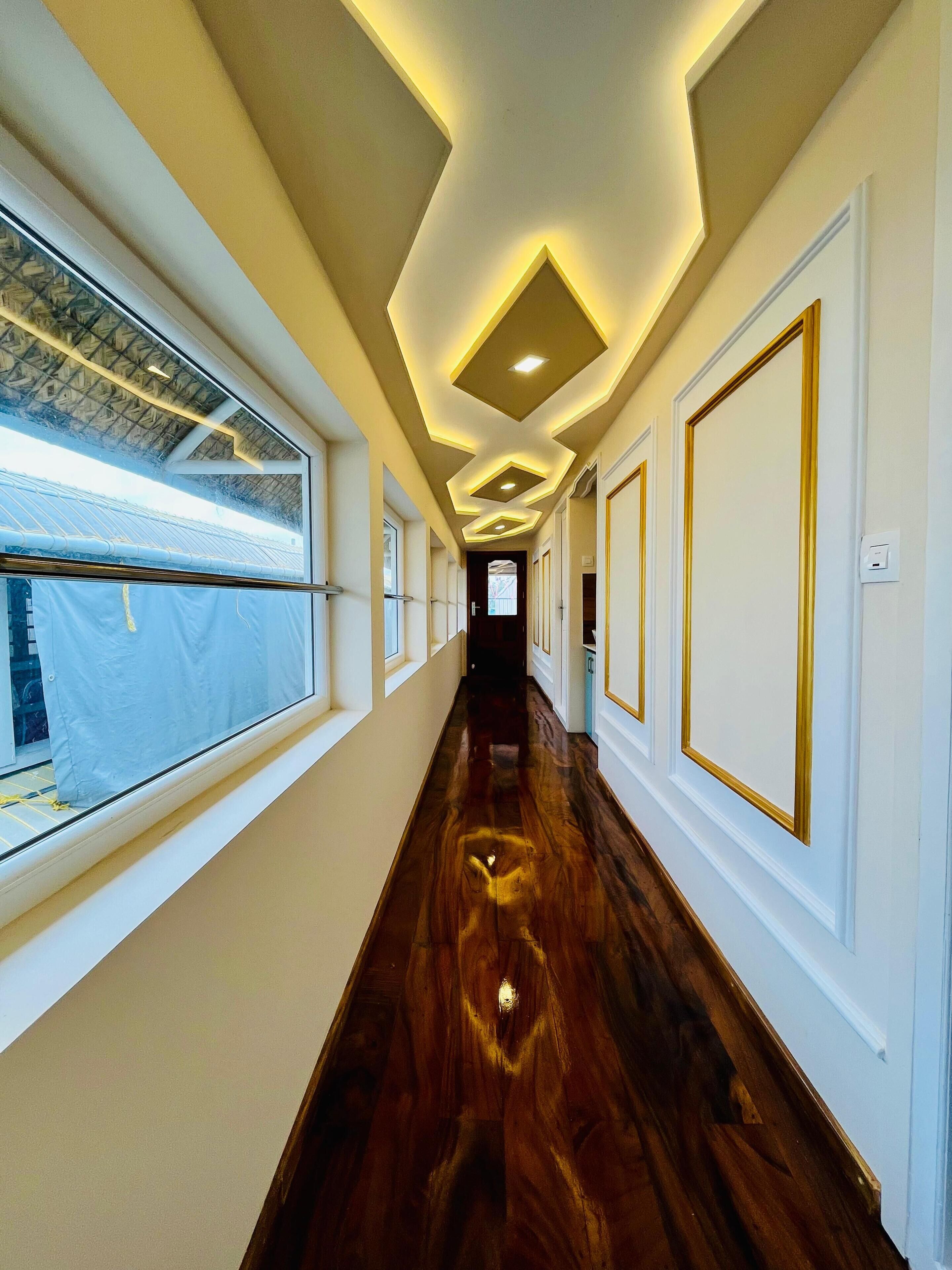 Un couloir doté d’un plancher en bois, de murs blancs et d’un plafond pourvu d’un éclairage encastré.