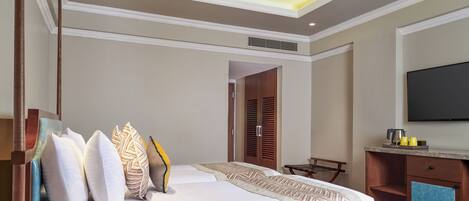 A hotel room with two beds, a ceiling fan, a TV, and a small kitchenette.
