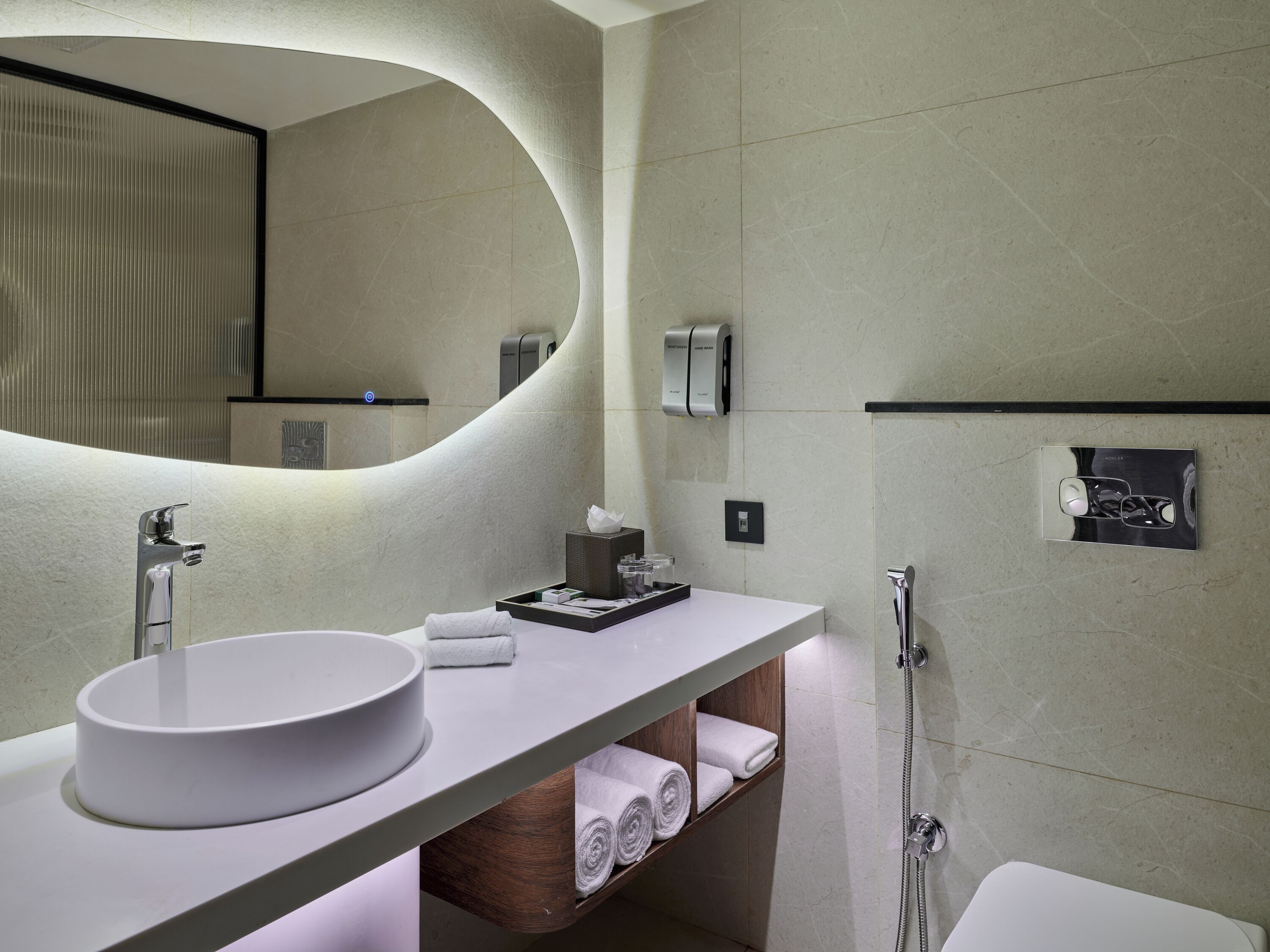 A modern bathroom with a large mirror, a round sink, a towel rack, and a shower.