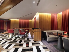 Un moderno vestíbulo de hotel con mostrador de recepción, zona de estar y un escenario.