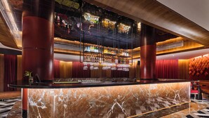 A bar area with a marble countertop, red pillars, and a variety of bottles and glasses. - Hotel Swosti Premium (Bhubaneshwar)