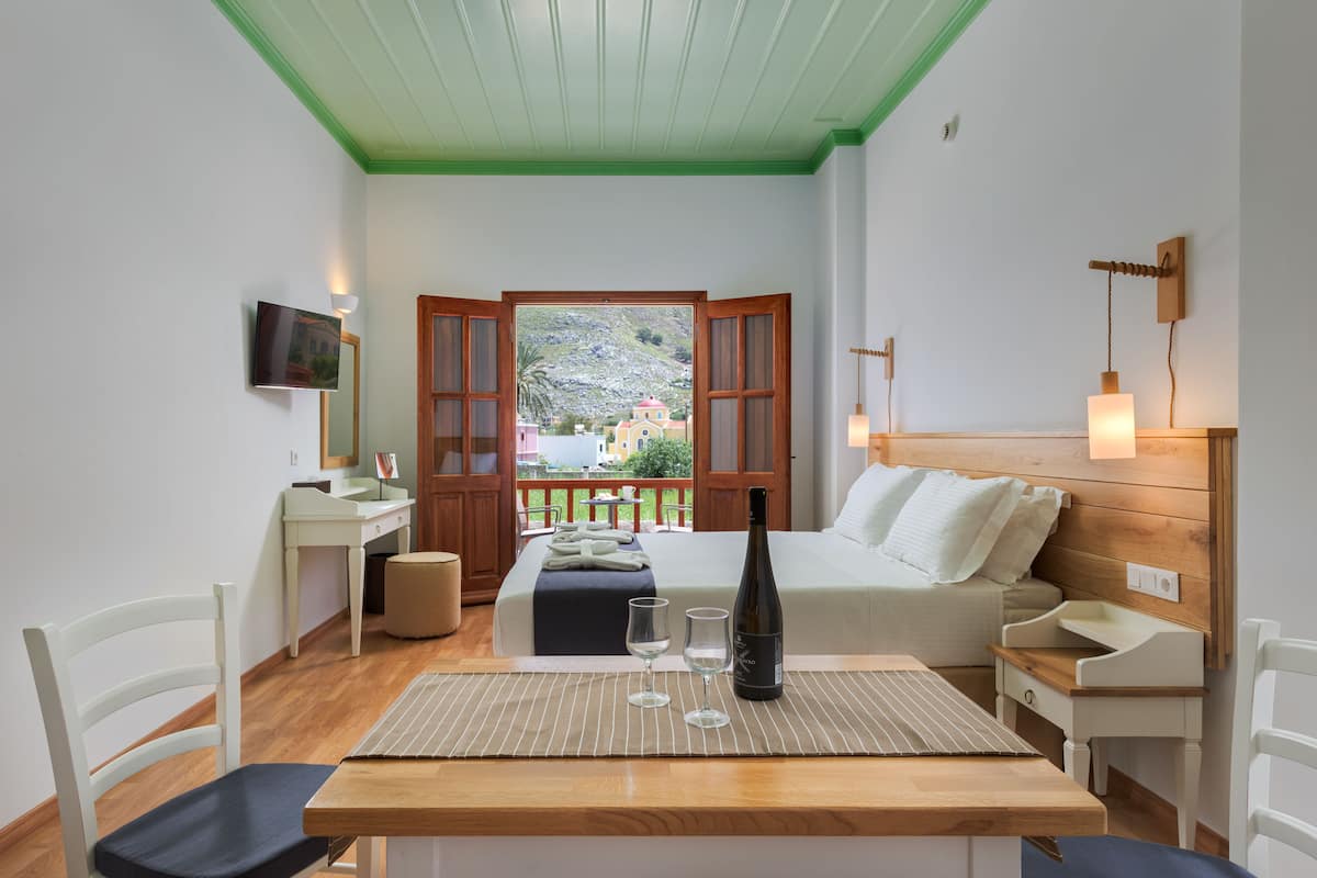 Habitación de hotel con cama, escritorio, silla, televisor y vista al exterior.