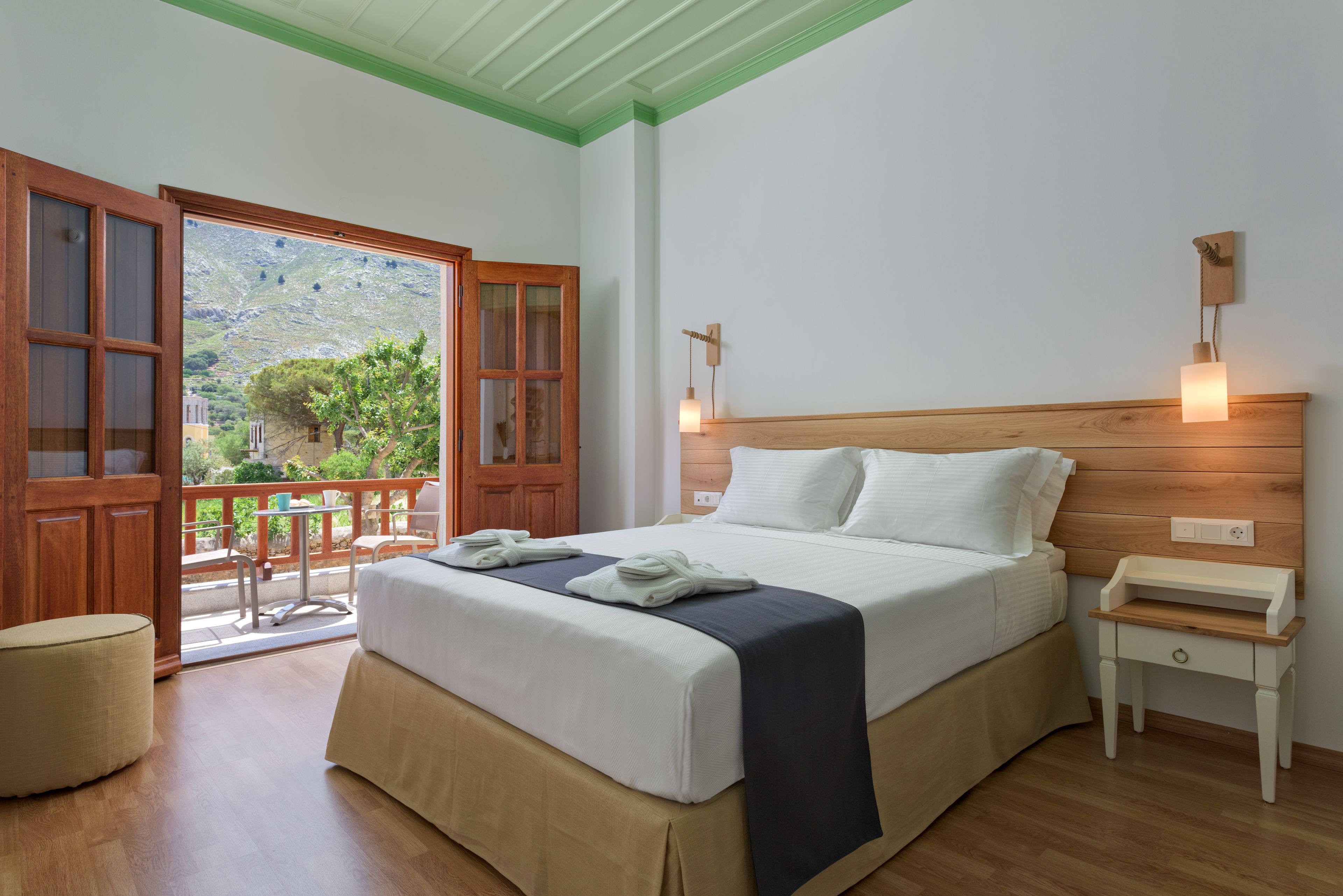 A bedroom with a bed, bedside table, and a view of the outdoors.