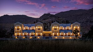 Un hotel grande y moderno con múltiples balcones y una fachada simétrica, con montañas al fondo.