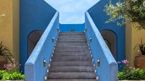 Una escalera con paredes de piedra y barandillas azules que sube a un nivel superior.