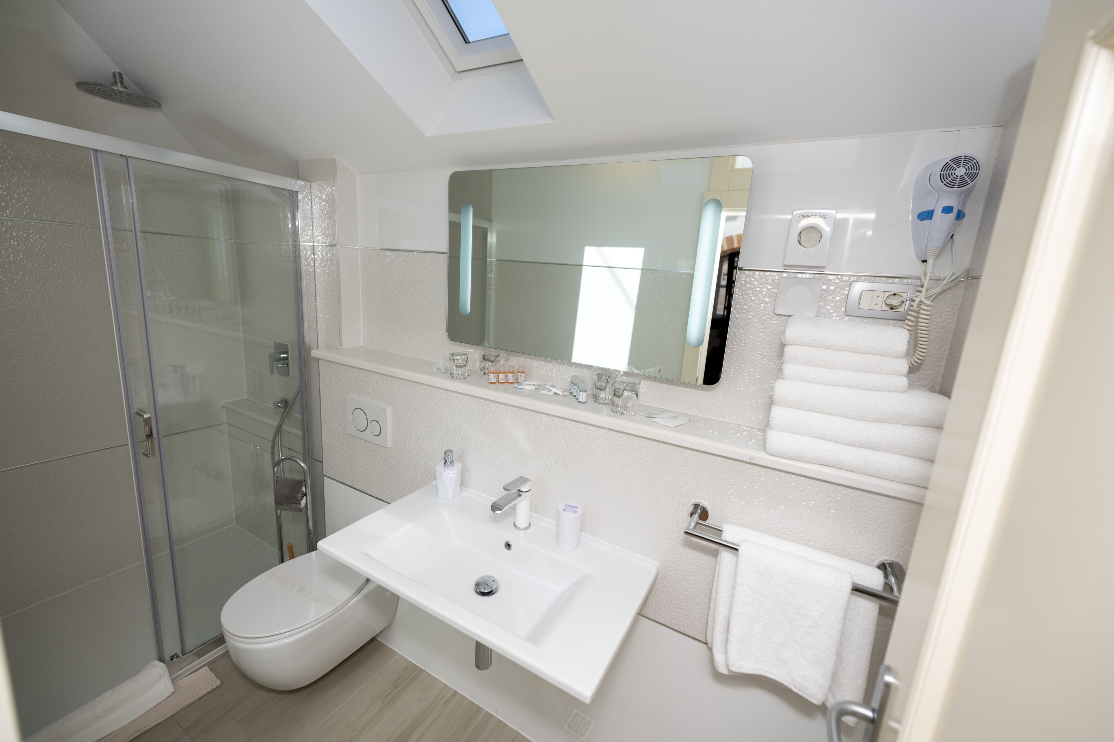 A modern bathroom with a glass-enclosed shower, a white sink, and a large mirror above it.