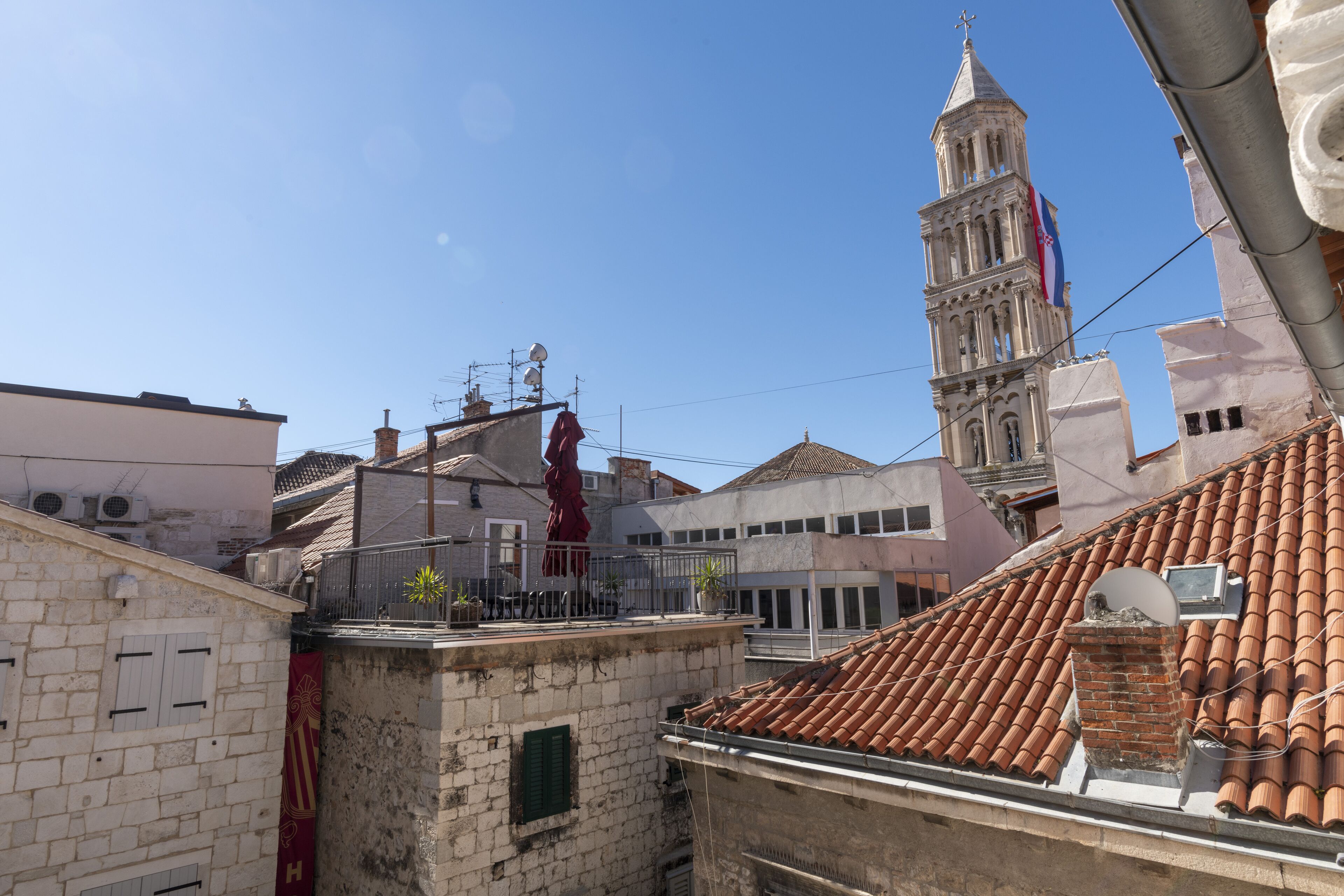 A view of a cityscape with a prominent tower and a building with a red roof.