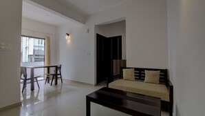 A modern living room with a sofa, a coffee table, and a dining area with chairs and a table.