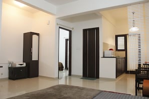 A modern hotel room with a large mirror, a kitchenette, a dining area, and a separate bathroom.
