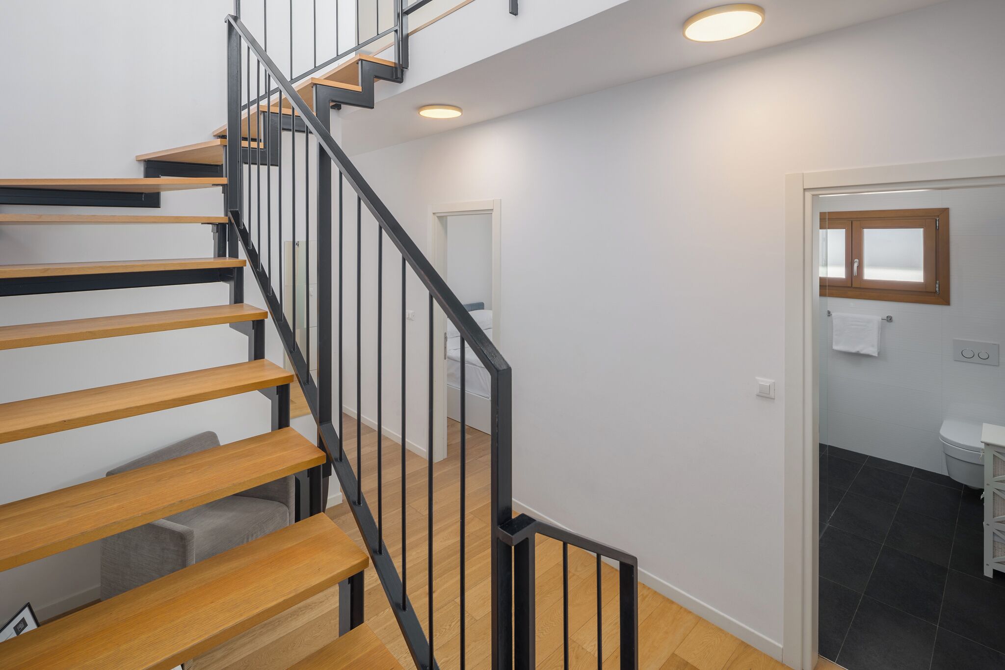 A modern staircase with wooden steps and black railings, leading to an upper floor.