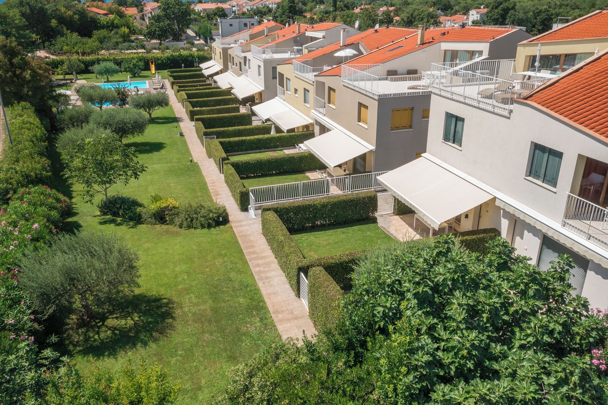 Une rangée d’immeubles résidentiels modernes dotés de balcons, d’une piscine et de jardins bien entretenus.