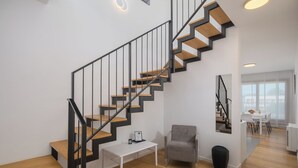 A modern interior with a staircase, a seating area, and a dining space. - Apartments Maj Residence Premium (Porec)