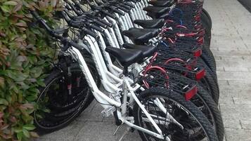 A row of bicycles parked outside a building with a door and a small window.
