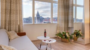 A room with a sofa, a small table with a bottle and glasses, and a view of a cityscape through large windows. - PRIMA Life Spalato (Split)