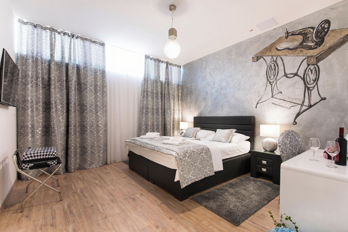 A modern bedroom with a large bed, bedside tables, a desk, and a chair.
