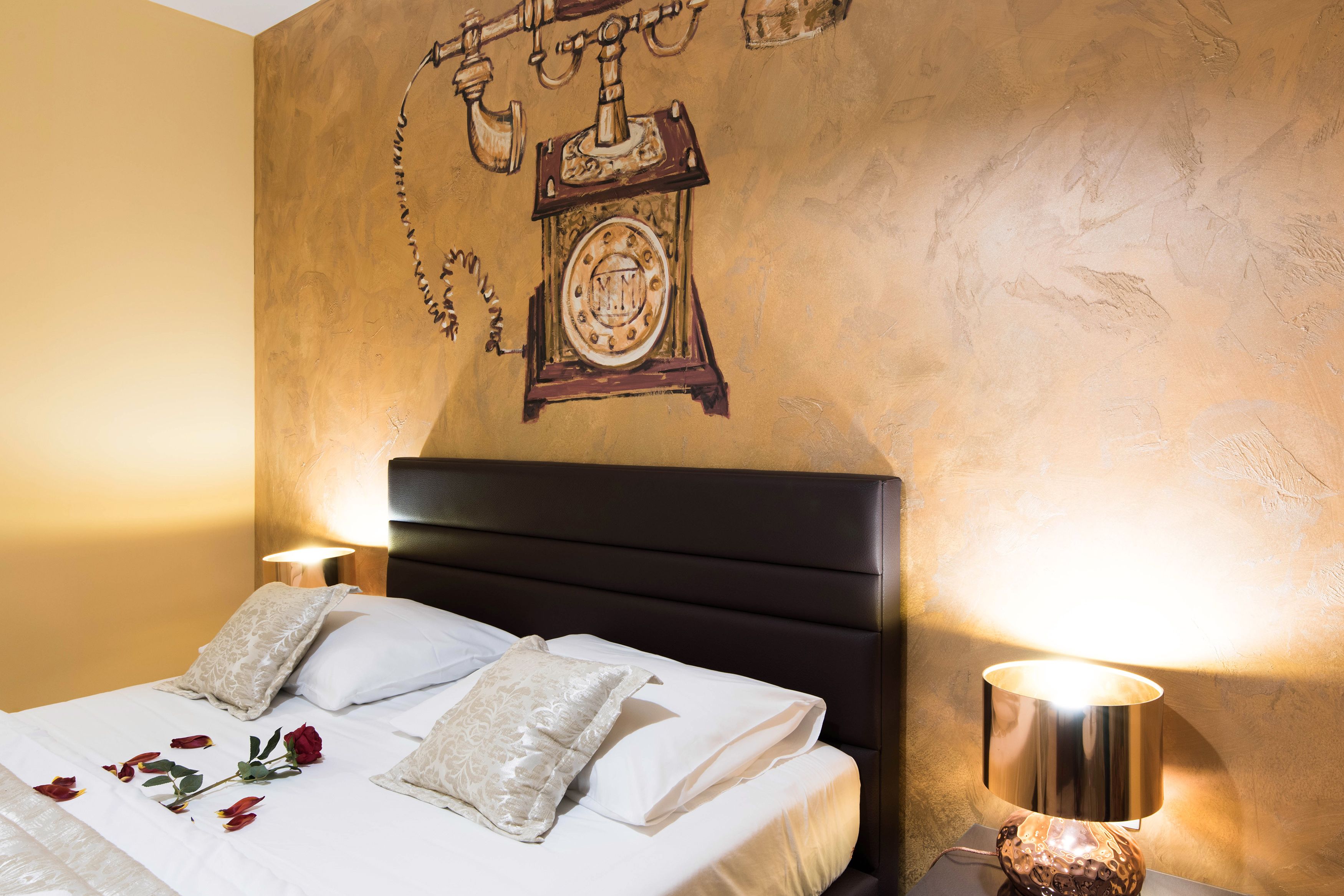 A hotel room with a bed, pillows, a bedside lamp, and a wall clock.