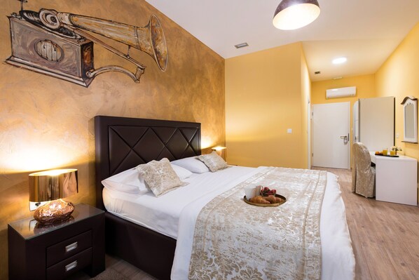 A hotel room with a bed, bedside tables, a nightstand, a mirror, and a breakfast tray.