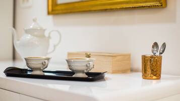 A white countertop with two white cups, a teapot, and a tray.