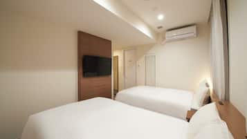 A hotel room with two beds, a TV, an air conditioning unit, and a wooden cabinet.