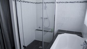 Un baño moderno con ducha de vidrio, una bañera blanca y piso de baldosas.