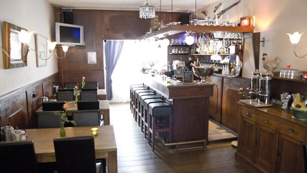 Ein Restaurant mit Barbereich, Holzmöbeln und einem an der Wand befestigten Fernseher.