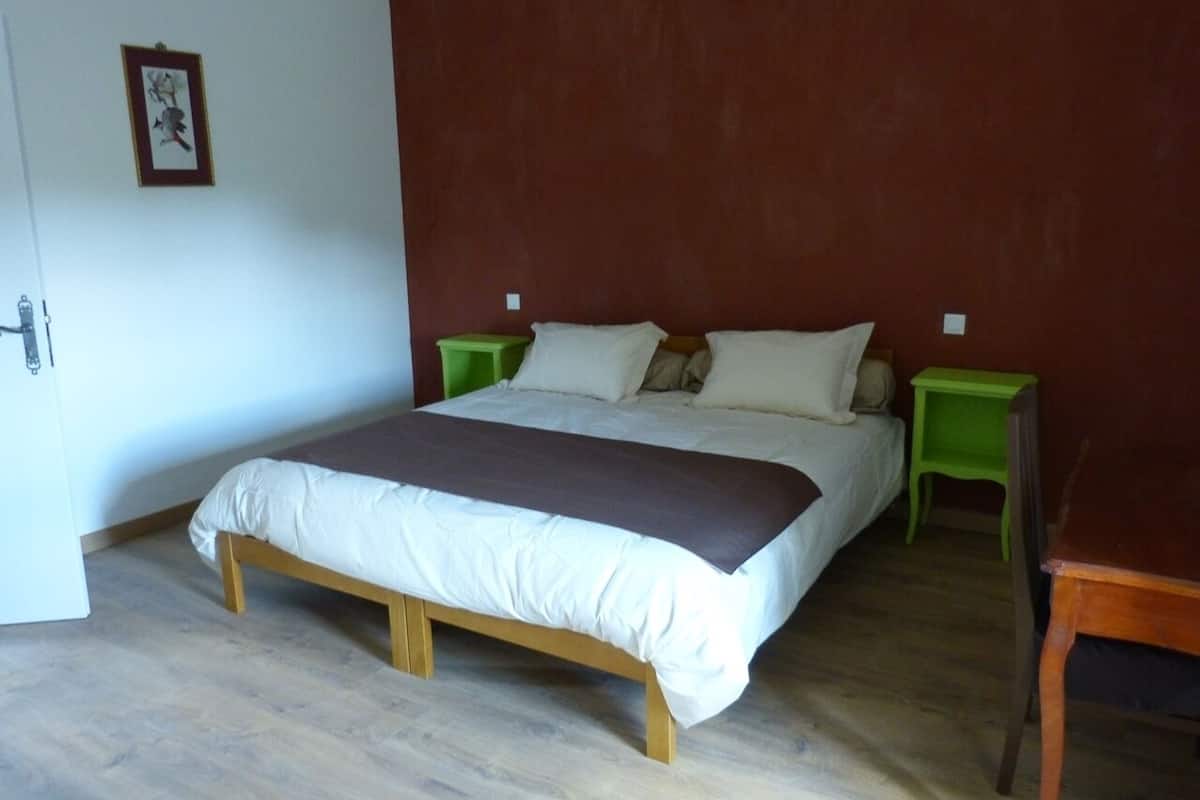 A single-bed room with a wooden frame, white bedding, and two green nightstands.