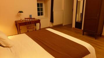 Ein Schlafzimmer mit Bett, Schreibtisch, Stuhl, Fenster, Heizkörper, Kleiderschrank und Spiegel.