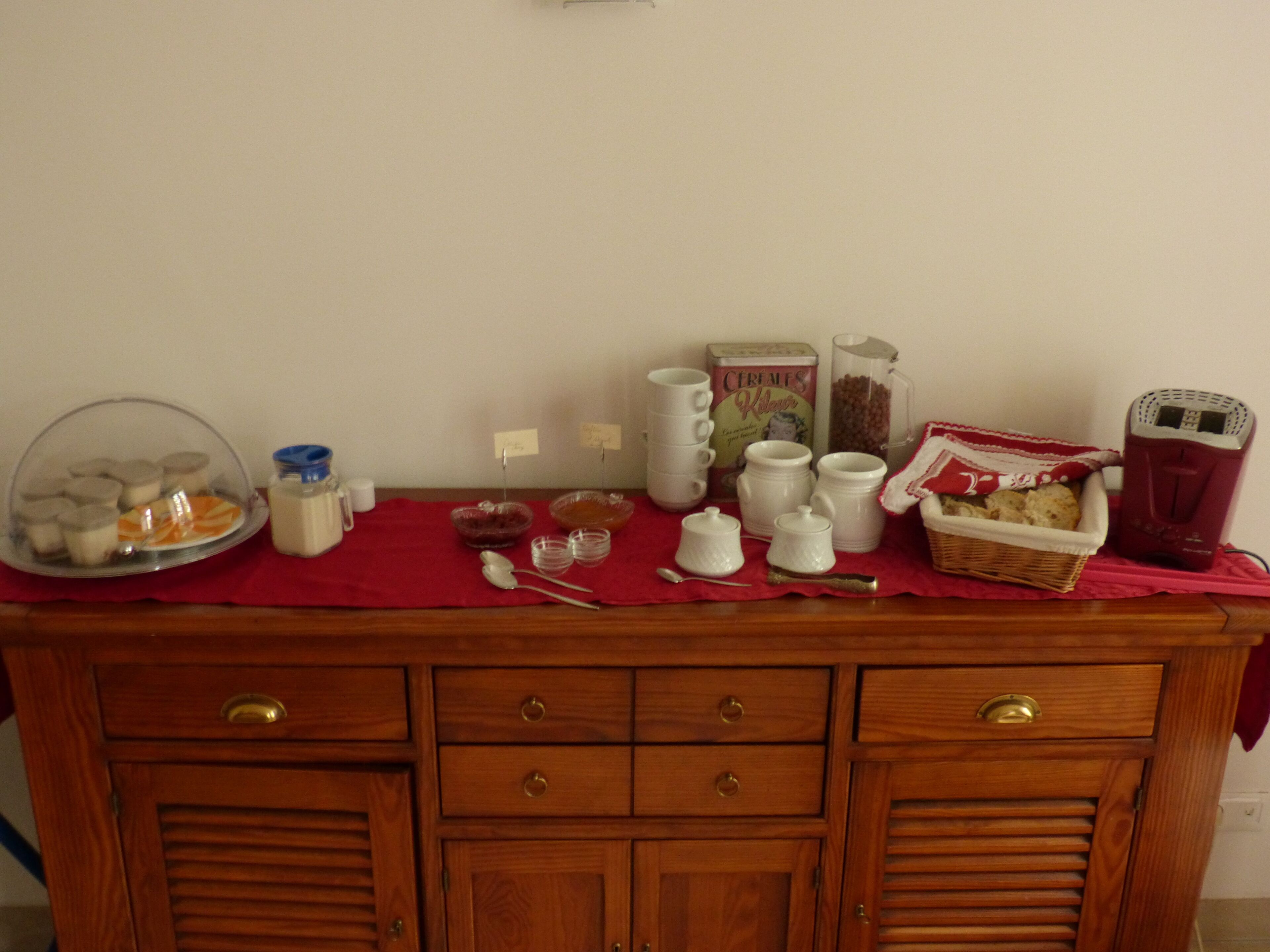 A wooden buffet table with various food items and containers, including a glass jar, bowls, and a basket.