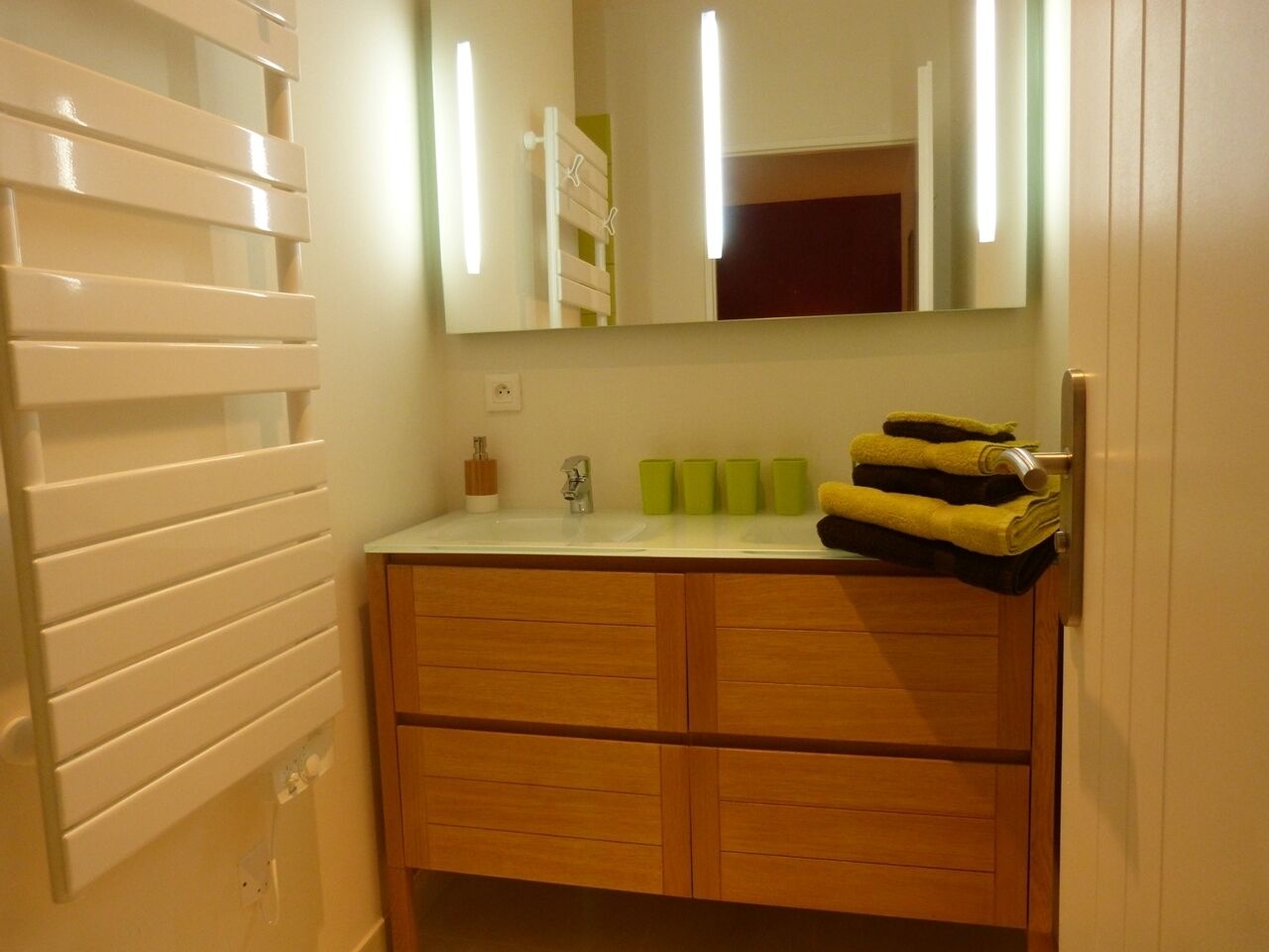 A bathroom with a wooden vanity, a mirror, and a sink.