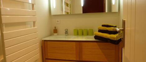 A bathroom with a wooden vanity, a mirror, and a sink.
